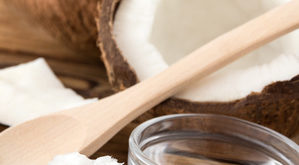 Kokosöl in Schale auf Tisch mit offener Kokosnuss
